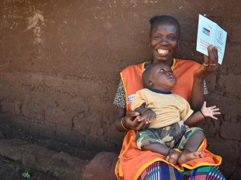 Joy, a World Vision Health Promoter, holds her vaccine certificate 